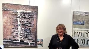 Margot Krämer vor einer Stellwand mit zwei Bildern